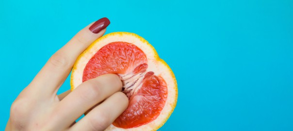 Two fingers on grapefruit on blue background. Sex concept.